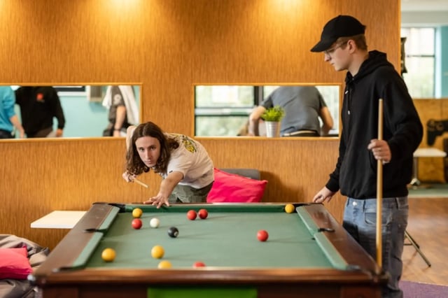 Two students play pool table area at Newport Student Village in Newport Student Accommodation
