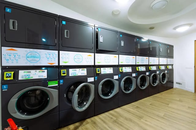 Washing machines and dryers stacked with digital displays Laundry room at St Peters Court in Nottingham Student Accommodation