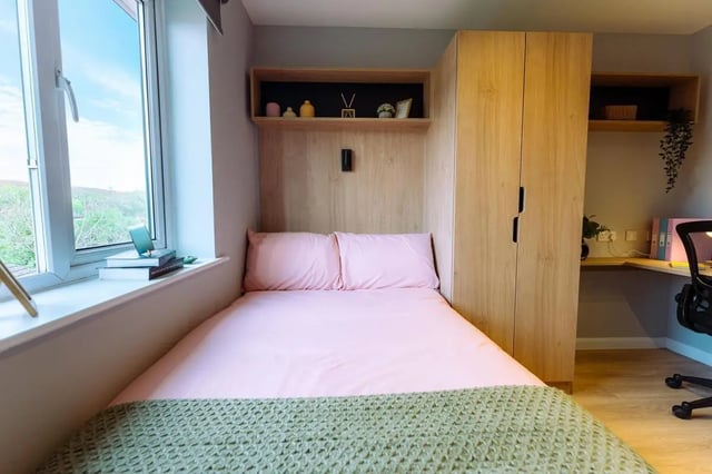 Pink bed with green throw and wooden wardrobe bedroom at St Peters Court in Nottingham Student Accommodation