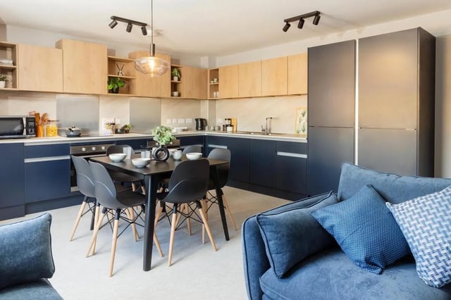 Dining table chairs kitchen cabinets refrigerator living room at St Peters Court in Nottingham Student Accommodation