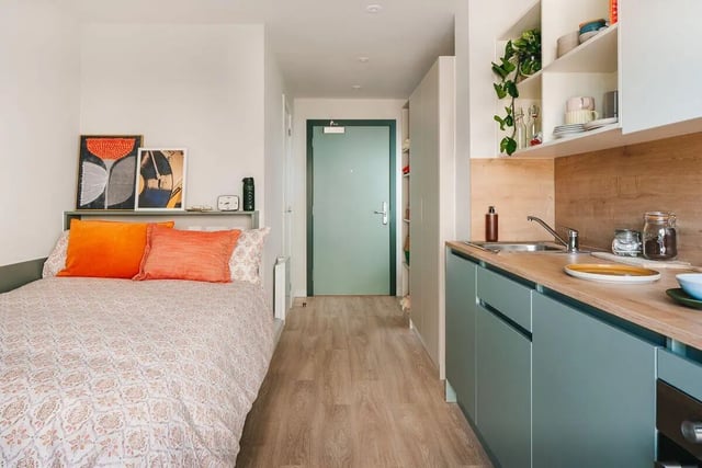 Bed with orange pillows and kitchen counter Kitchen at City Wharf in Glasgow Student Accommodation