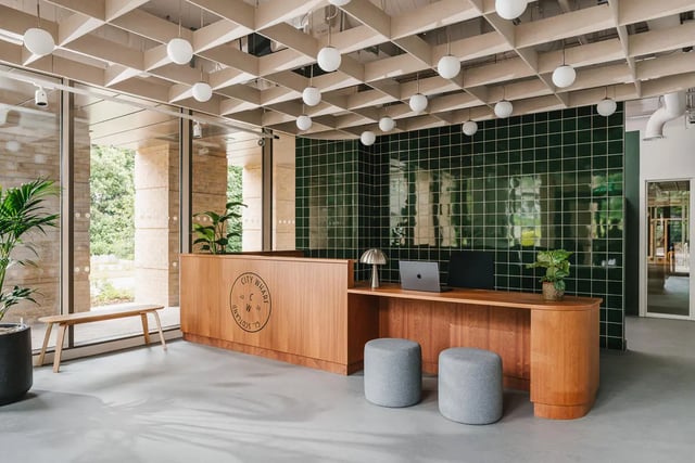 Wooden reception desk with stools and plants lobby at City Wharf in Glasgow Student Accommodation