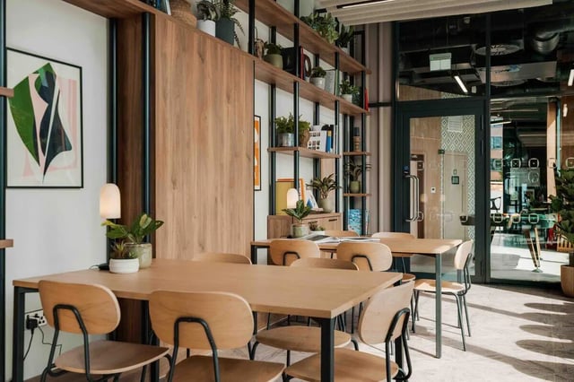 Wooden tables and chairs art plants common area living room at Fusion Manchester in Manchester Student Accommodation