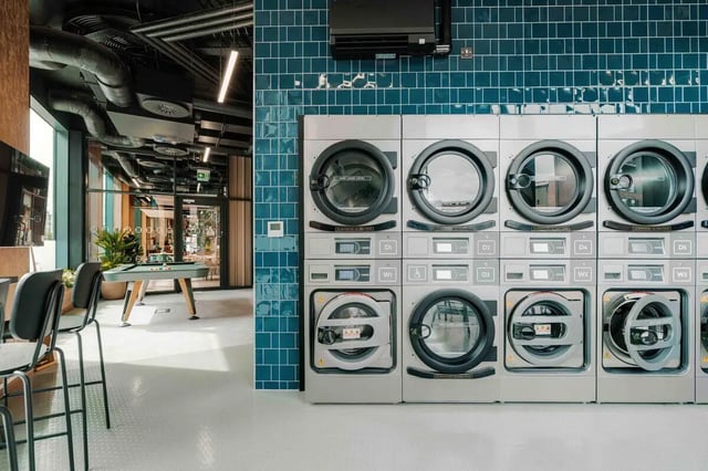 Stacking washing machines on blue tile laundry area at Fusion Manchester in Manchester Student Accommodation
