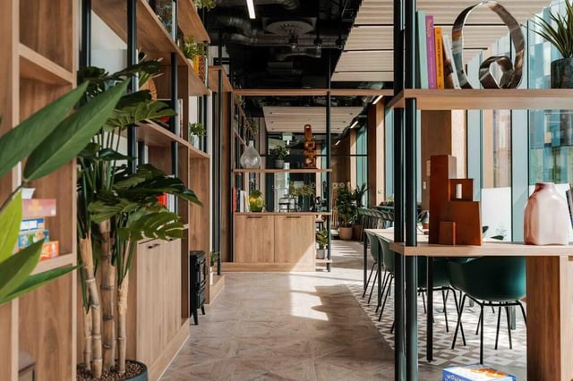 Bookshelves plants tables and chairs communal area at Fusion Manchester in Manchester Student Accommodation