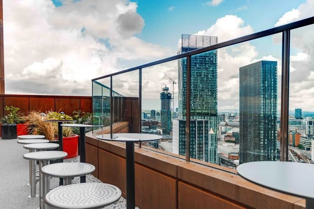 Outdoor tables and potted plants with city view exterior at Fusion Manchester in Manchester Student Accommodation