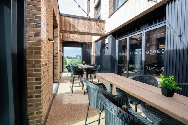 Outdoor tables and chairs with brick building exterior at Fusion Students Brent Cross in London Student Accommodation