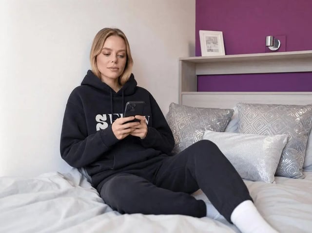 Woman on bed with phone bedroom interior at Unity Square in Liverpool Student Accommodation