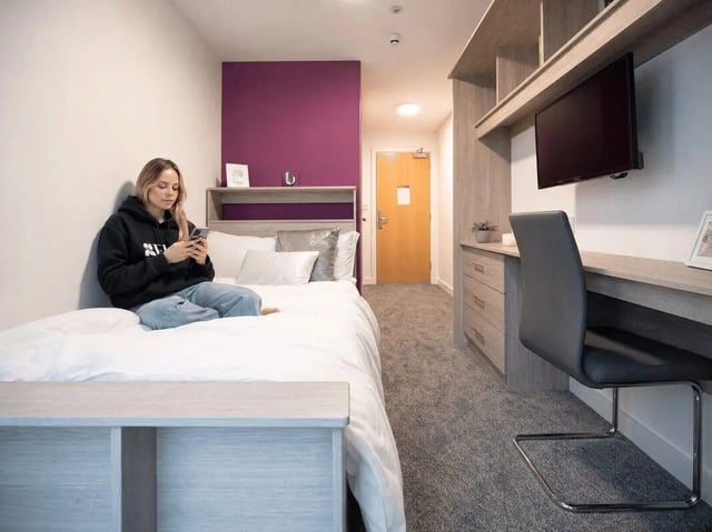 Student sits on bed at desk with TV Bedroom at Unity Square in Liverpool Student Accommodation