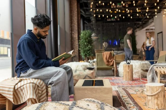 Man reading book in lounge with people living room at Fusion Students Nottingham in Nottingham Student Accommodation