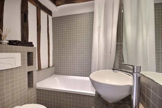 Tiled bathtub and sink with wooden beams bathroom at Studio in Rue de Bourgogne, 75007 Paris, France in Paris Student Accommodation
