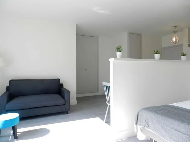 Dark sofa blue stool and white partition Living room at Studio in Rue Lecourbe, 75015 Paris, France in Paris Student Accommodation