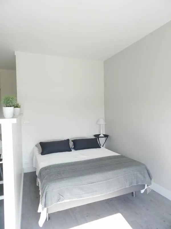 Bed with grey throw and plants bedroom at Studio in Rue Lecourbe, 75015 Paris, France in Paris Student Accommodation