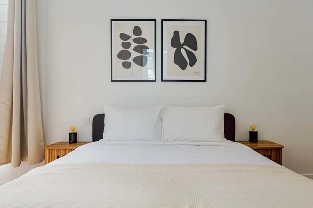 Bed with white linens two framed artworks bedside lamps bedroom at Apartment in 2 Rue de Miromesnil, 75008 Paris, France in Paris Student Accommodation