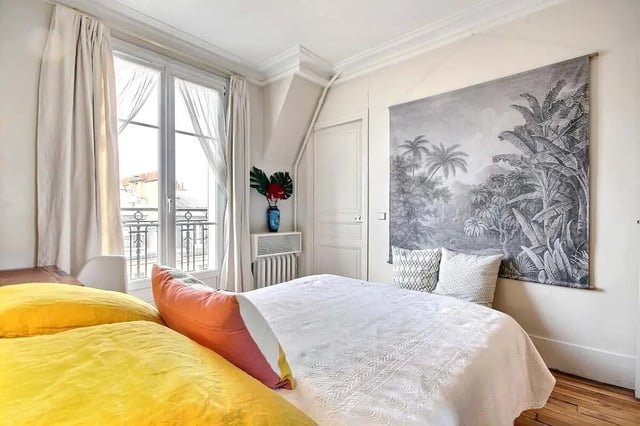 Bed with yellow and orange pillows tropical tapestry bedroom at Apartment in Rue Régis, 75006 Paris, France in Paris Student Accommodation