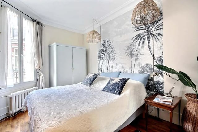 Bed with patterned quilt and palm wallpaper bedroom at Apartment in Rue Régis, 75006 Paris, France in Paris Student Accommodation