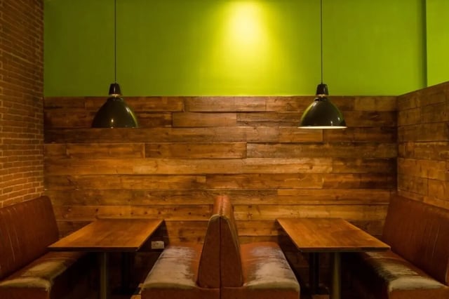 Wooden tables and booths with pendant lights seating area at Lyme Regis House in Bournemouth Student Accommodation