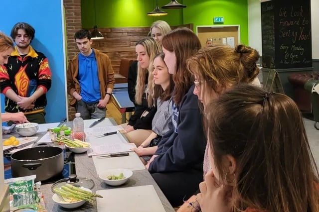 Students preparing food with asparagus and ingredients kitchen at Lyme Regis House in Bournemouth Student Accommodation
