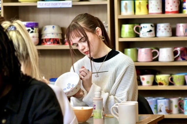 Girl paints bowl on shelves with mugs activity at Lyme Regis House in Bournemouth Student Accommodation