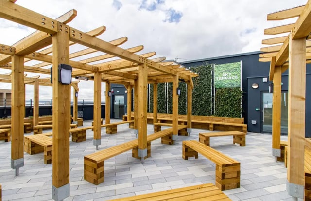 Wooden pergolas with benches on paved terrace outdoor area at Skyline in Bournemouth Student Accommodation