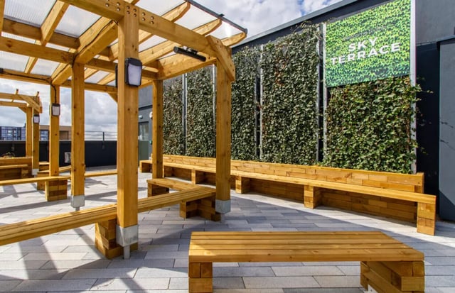 Wooden benches under a pergola with a green wall at Skyline in Bournemouth Student Accommodation
