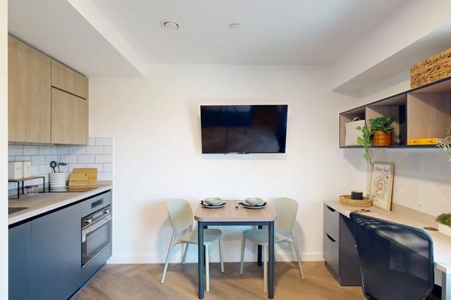 Dining table chairs kitchen cabinets television desk living area at Bridgeside in Nottingham Student Accommodation