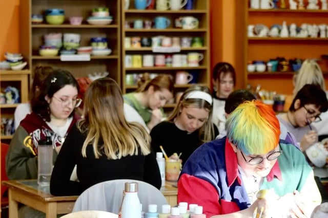 Students painting pottery at tables with shelves Ceramic Studio at Bournemouth University Village - Chesil House in Bournemouth Student Accommodation