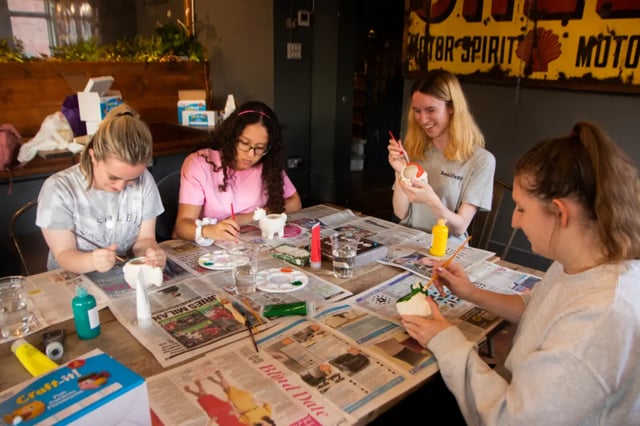 Students painting pottery on newspaper table common room at Cranborne House in Bournemouth Student Accommodation