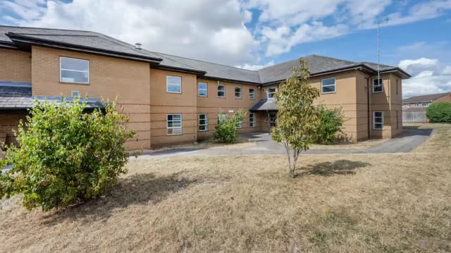 Tan brick building with many windows exterior at Hardwick Campus in Cheltenham Student Accommodation