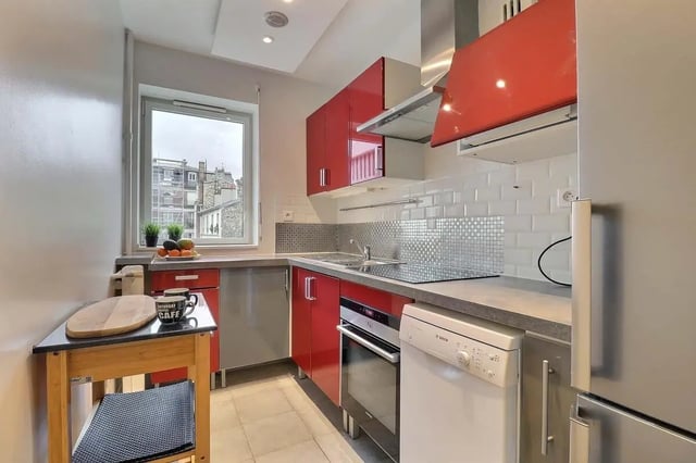 Red cabinets oven dishwasher and window kitchen at Apartment in Pass. du Guesclin, 75015 Paris, France in Paris Student Accommodation