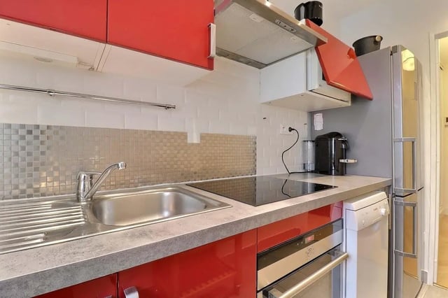 Red cabinets sink induction hob and fridge kitchen at Apartment in Pass. du Guesclin, 75015 Paris, France in Paris Student Accommodation