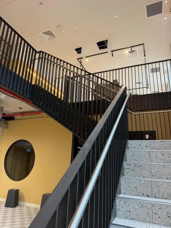 Modern staircase with black railings and yellow wall Area at The Switch Lachlan Macquarie Park in Sydney Student Accommodation