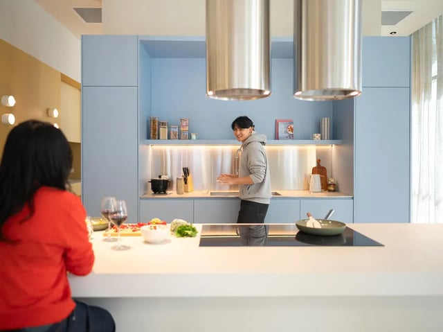 Students cooking in a modern blue kitchen with island at The Switch Lachlan Macquarie Park in Sydney Student Accommodation