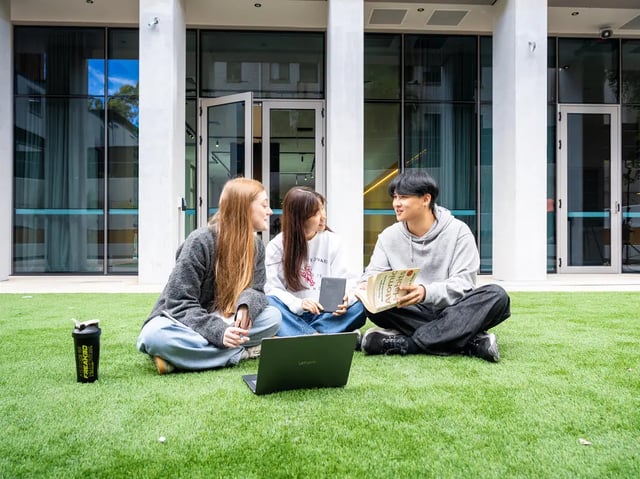 Students studying together on grass exterior at The Switch Lachlan Macquarie Park in Sydney Student Accommodation