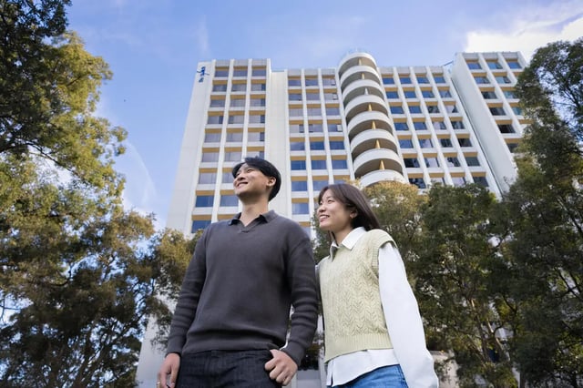 Two students stand before a building exterior at The Switch Lachlan Macquarie Park in Sydney Student Accommodation