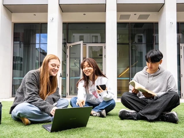Three students study outside on grass exterior at The Switch Lachlan Macquarie Park in Sydney Student Accommodation