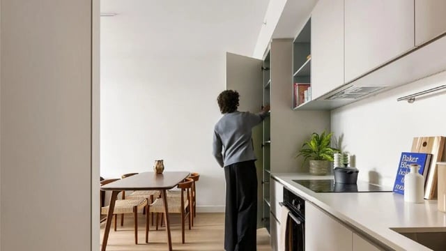 Person accessing pantry next to dining table and kitchen area at Assemble Swiftwalk in Melbourne Student Accommodation