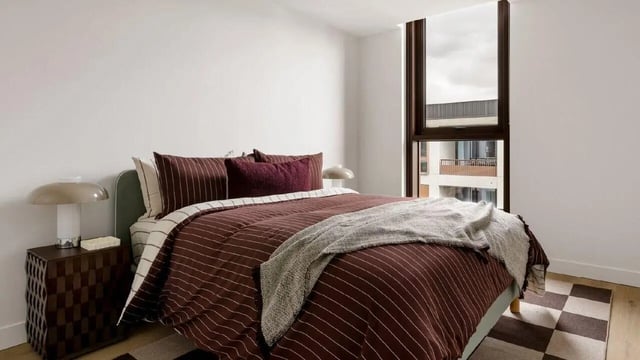 Bed with striped duvet and pillows nightstand lamp Bedroom at Assemble Swiftwalk in Melbourne Student Accommodation