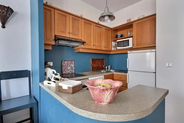 Kitchen with blue walls wooden cabinets and refrigerator kitchen at Apartment in Rue Bergère, 75009 Paris, France in Paris Student Accommodation
