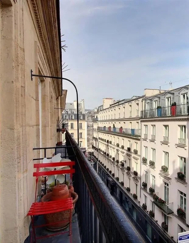 Red chair plants pots overlooking city balcony exterior at Apartment in Rue Bergère, 75009 Paris, France in Paris Student Accommodation