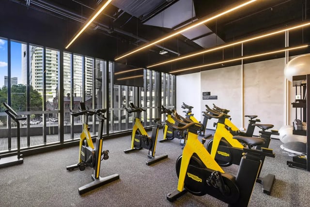 Yellow stationary bikes and treadmill fitness room at West Tower, Melbourne Quarter in Melbourne Student Accommodation