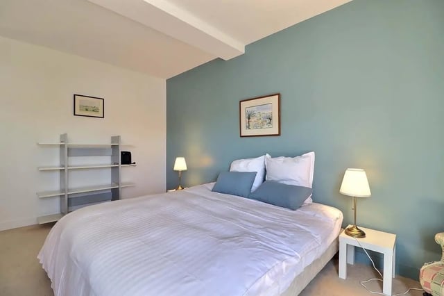 Bed with white linens two blue pillows bedside lamps bedroom at Apartment in Rue César Franck, 75015 Paris, France in Paris Student Accommodation
