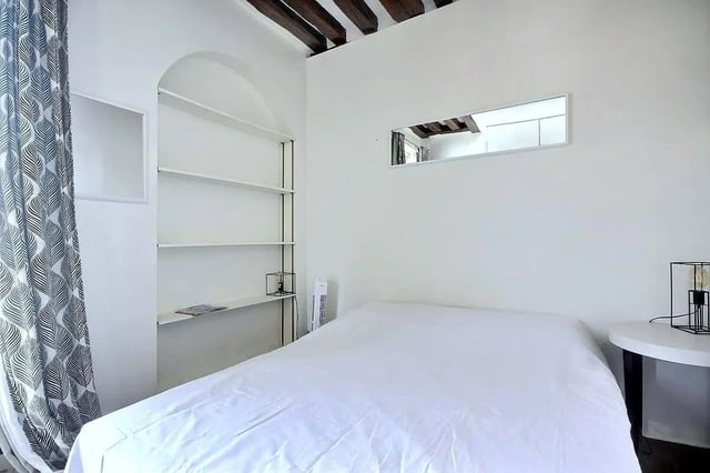 White duvet shelves curtain bedside table lamp bedroom at Apartment in Rue Dauphine, 75006 Paris, France in Paris Student Accommodation