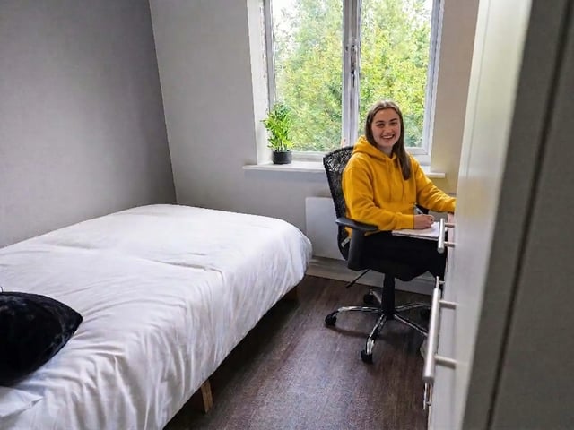 Student studying at desk beside bed bedroom at Moss Court in Manchester Student Accommodation