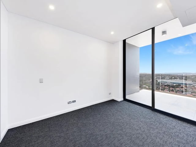 Empty white room with grey carpet and balcony exterior at Belong Eastgardens in Sydney Student Accommodation