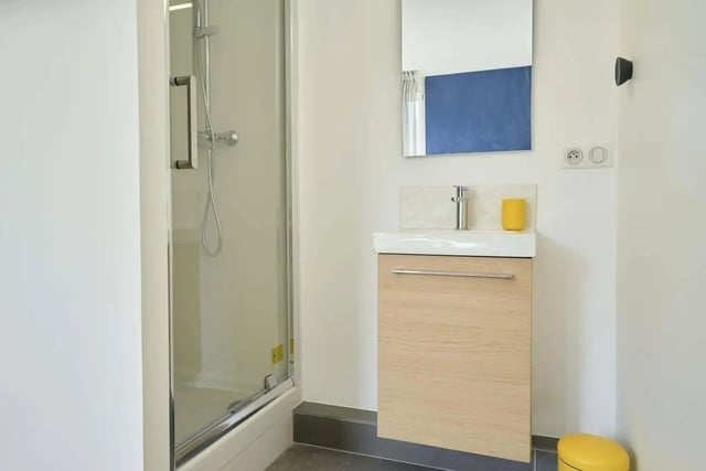 Shower sink mirror cabinet and yellow bin bathroom at Room in 121 Rue Haxo, 75019 Paris, France in Paris Student Accommodation