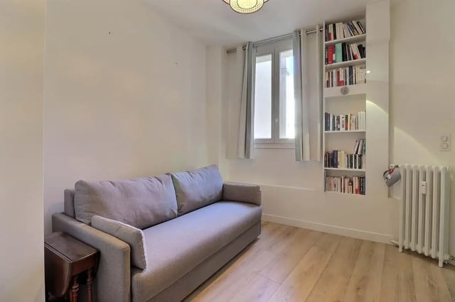 Sofa bookshelf window radiator living room at Apartment in Rue Villaret de Joyeuse, 75017 Paris, France in Paris Student Accommodation