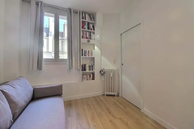 Grey sofa radiator bookshelf window living room at Apartment in Rue Villaret de Joyeuse, 75017 Paris, France in Paris Student Accommodation