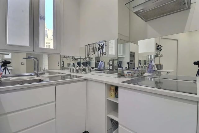 Modern white kitchen with mirrored backsplash and appliances kitchen at Apartment in Rue Villaret de Joyeuse, 75017 Paris, France in Paris Student Accommodation