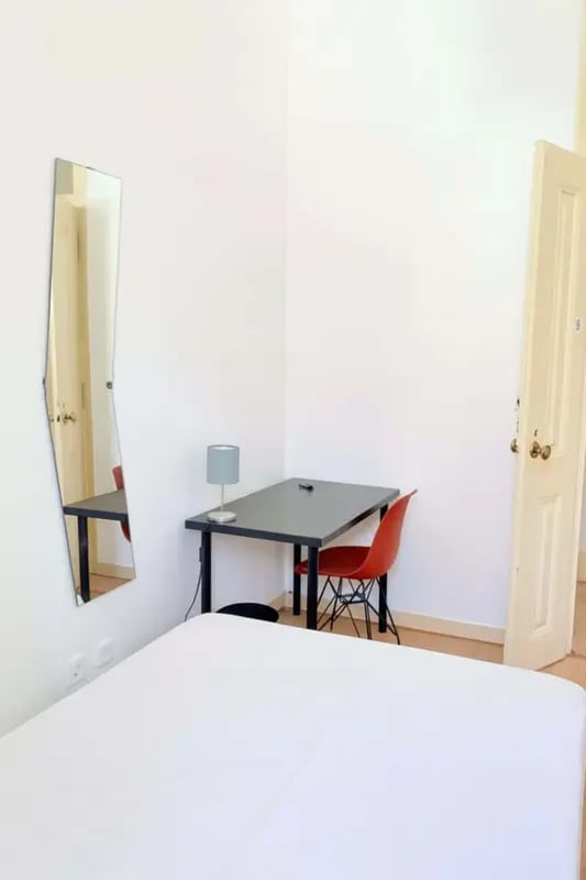 Bed desk lamp red chair mirror bedroom at Quarto com cama de casal em apartamento com 8 quartos - FLAT G - G08 in Lisbon Student Accommodation